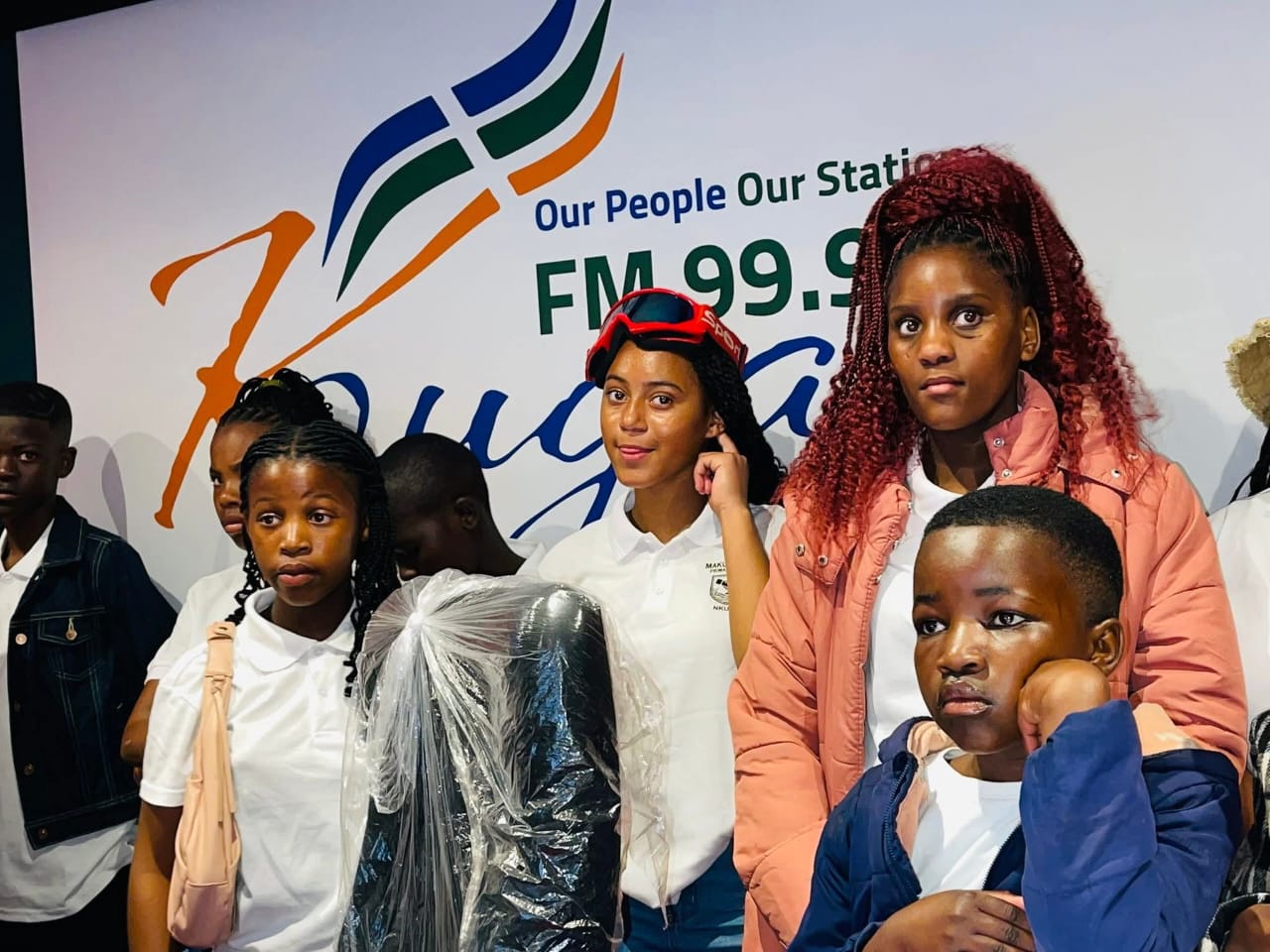 Group of learners at the Kouga FM 99.9 station banner