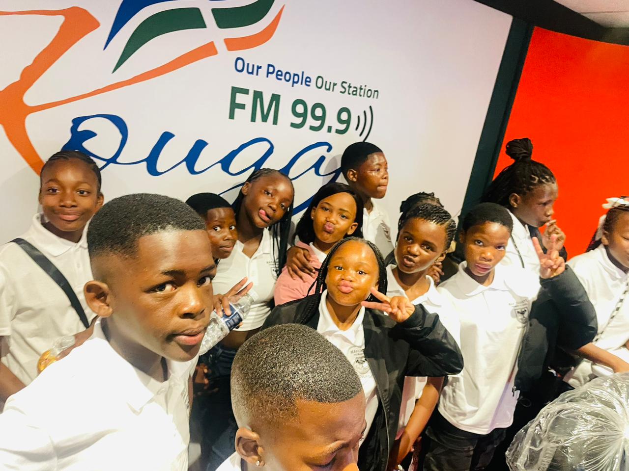 Learners taking a selfie at the Kouga FM 99.9 banner