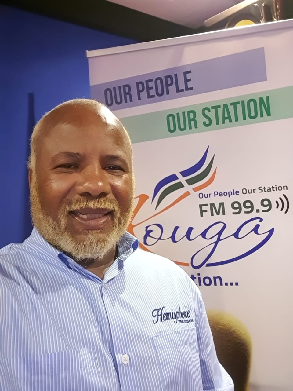 Kouga FM presenter at the Our People Our Station banner