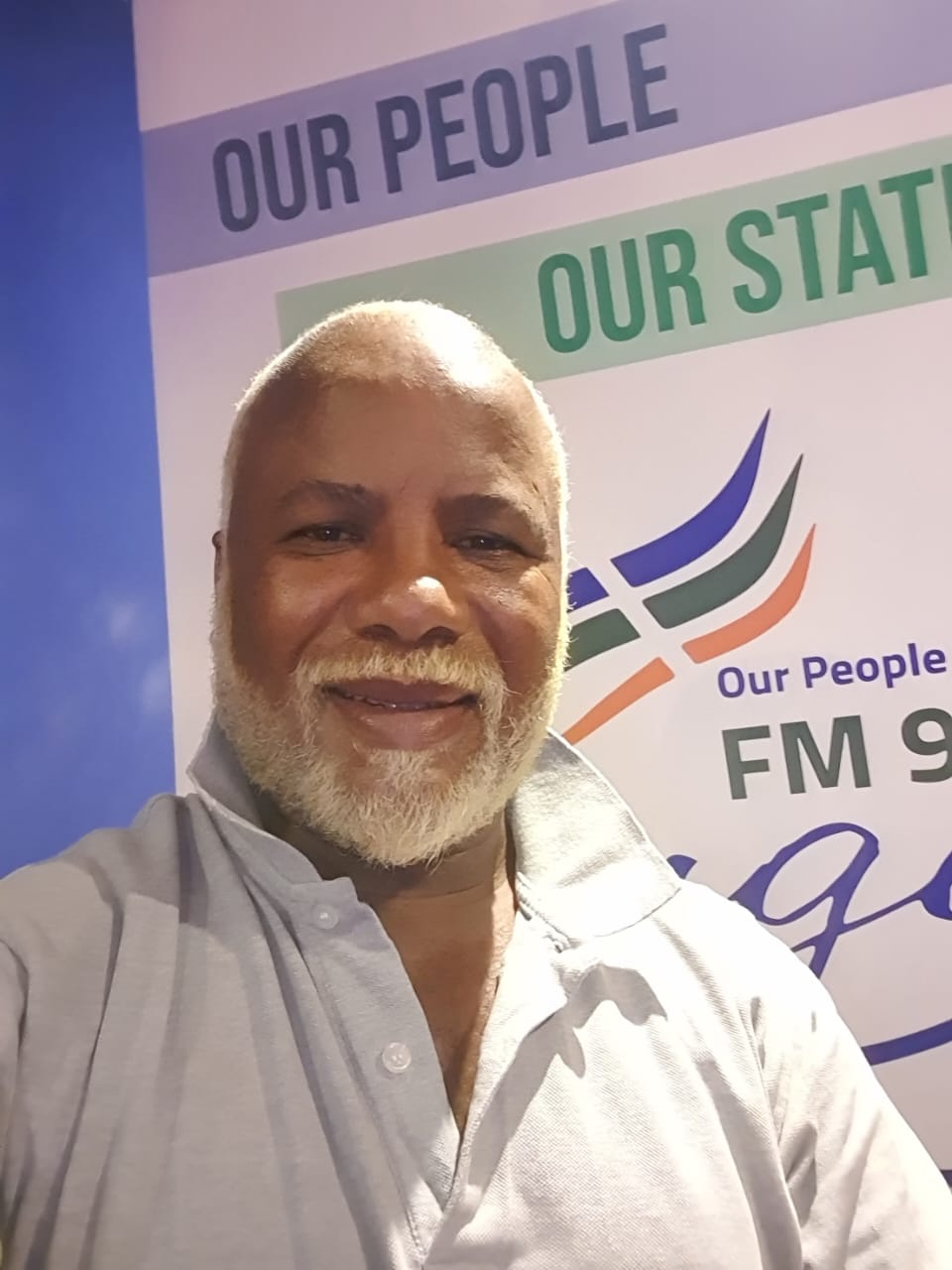 Kouga FM presenter selfie in front of the Our People Our Station banner